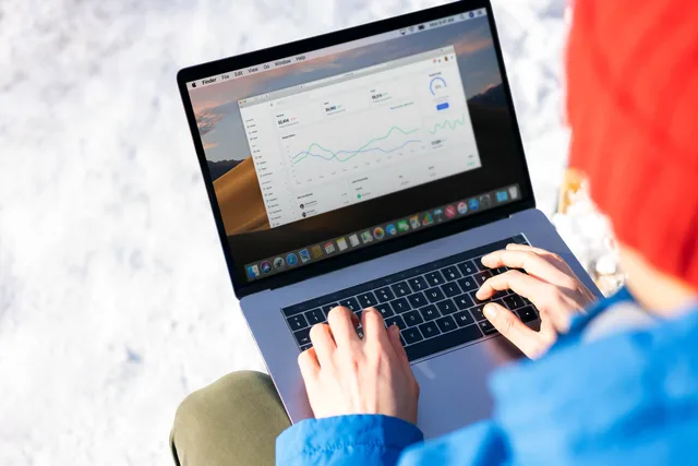 A person in a blue jacket analyzing business analytics on a laptop outdoors during winter. Branchenøgletal fra offentlige kilder: Hvordan sammenligner du din virksomhed med branchen?