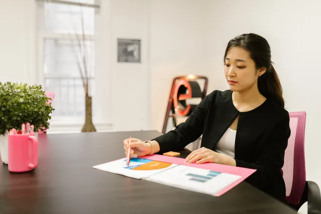 Woman in business attire analyzing documents at her office desk with reports and graphs. Dobbelt væsentlighedsanalyse: Sådan gennemfører du den trin for trin