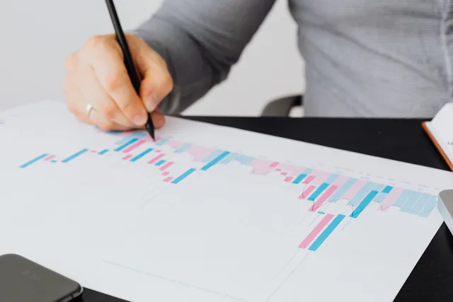 Close-up of a man writing on a printed chart indoors, analyzing colorful data. Erhvervsstatistik og offentlige nøgletal: Hvad undersøgelser viser